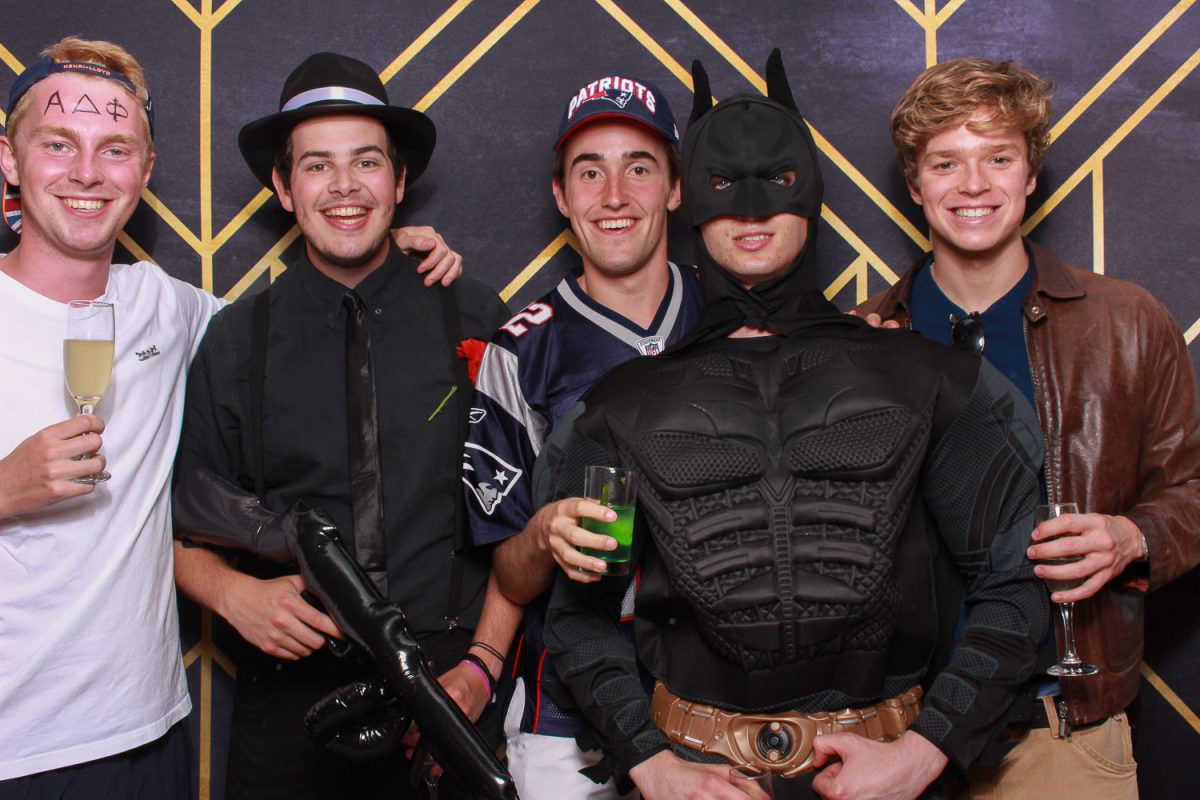 Group of makes in fancy dress at 21st birthday party in luxury photo booth