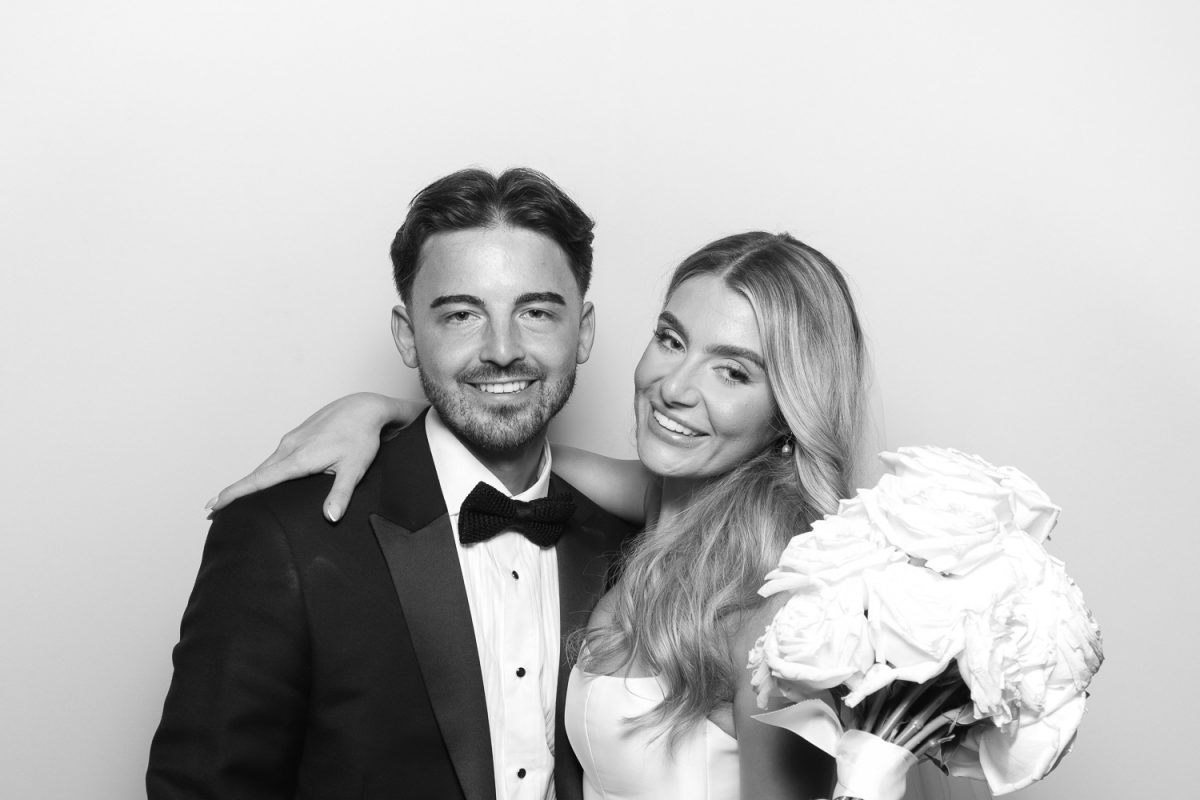 Black and White Photo Booth with wedding couple in the picture. Groom is wearing a tuxedo and the bride is holding her bouquet.
